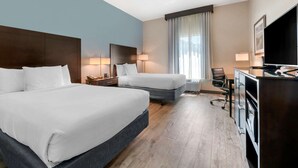 Ein Hotelzimmer mit zwei Betten, einem Schreibtisch, einem Stuhl und einem Fernseher.