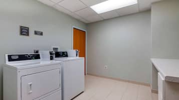Un lavadero con dos lavadoras y secadoras Maytag, una puerta de madera y un interruptor de luz en la pared.