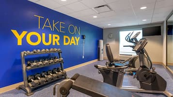 A gym with a blue wall, a bench, dumbbells, and exercise equipment.