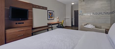 Ein Hotelzimmer mit Bett, Schreibtisch, Stuhl, Fernseher und Duschbereich.