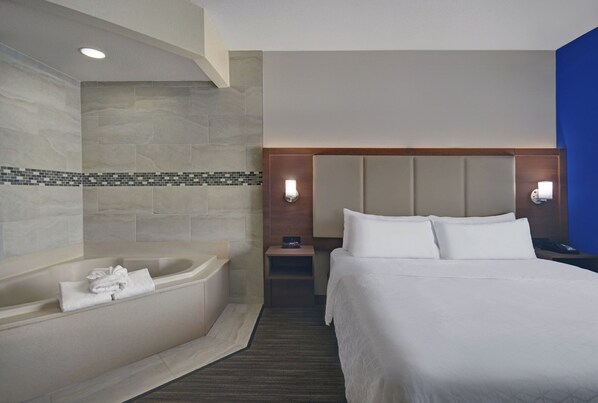 A hotel room with a large bed, a bathtub, and a nightstand with a lamp. - Holiday Inn Express Marshall by IHG (Marshall)