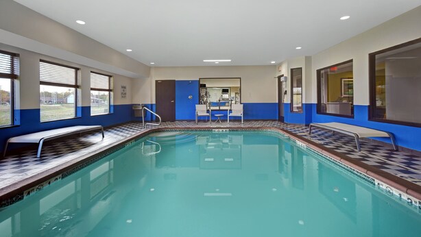 A swimming pool with a checkered tile edge, a bench, and a changing room area. - Holiday Inn Express Marshall by IHG (Marshall)