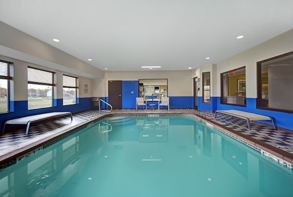 Une piscine dont le bord est orné de carreaux aux motifs géométriques, avec un banc et un espace vestiaire.