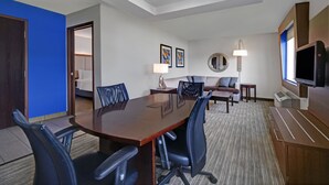 A conference room with a large wooden table, black office chairs, a sofa, and a television on a wooden cabinet. - Holiday Inn Express Marshall by IHG (Marshall)