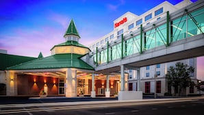 Un hotel con un edificio de techo verde, una entrada cubierta y una extensión con paredes de vidrio.
