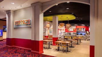 A restaurant interior with a red and white color scheme, multiple dining tables, and a visible kitchen area.