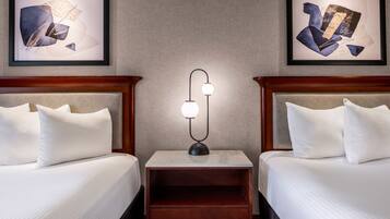 Habitación de hotel con dos camas, una mesita de noche con lámpara y obras de arte en las paredes.