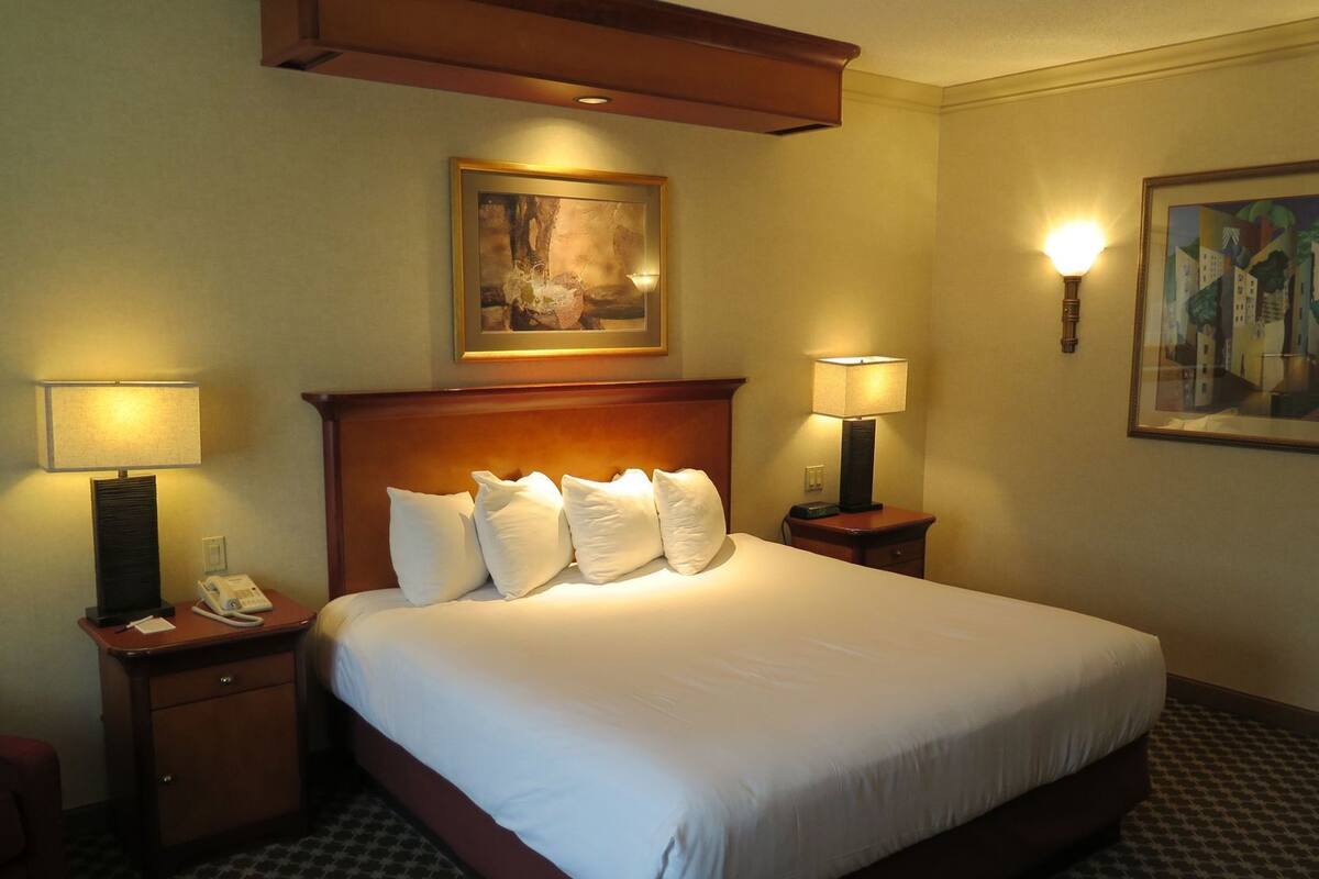 A hotel room with a large bed, two bedside tables with lamps, a telephone, and artwork on the walls.