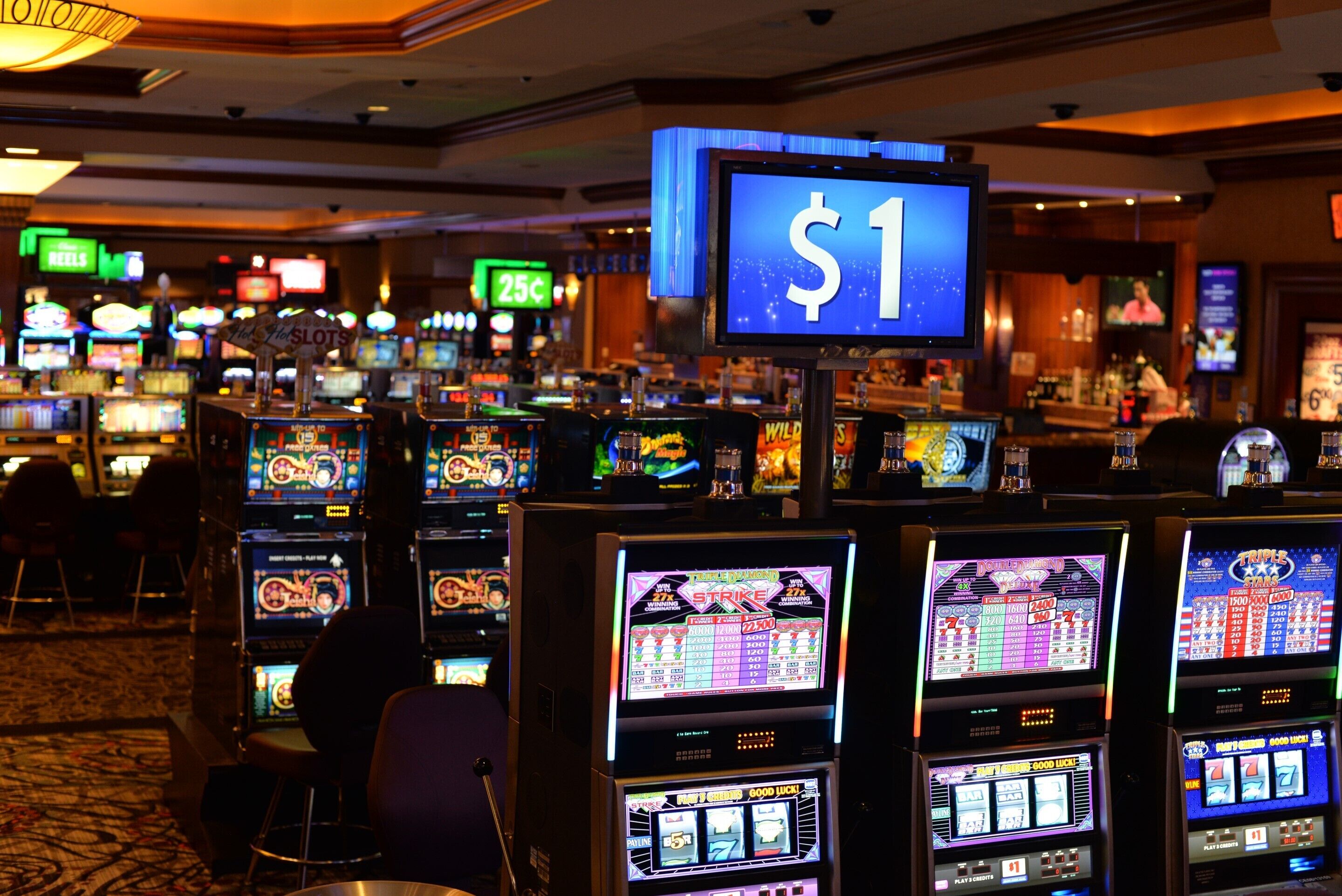 A casino with multiple slot machines and a sign indicating a $1 bet.