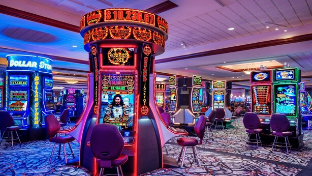 A casino floor with various slot machines, including 'DOLLAR STORM' and 'JACKPOT' games, and multiple gaming tables. - Harrah's Joliet Hotel & Casino - A Caesars Rewards Destination (Joliet)