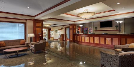 A hotel lobby with a reception desk, seating area, and a television mounted on the wall.