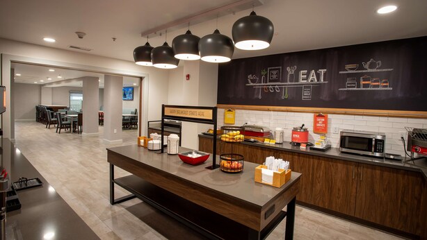A modern breakfast area with a counter, seating, and a chalkboard menu. - Hampton Inn Seaford (Seaford)