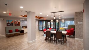 A modern dining area with a large table, chairs, and pendant lighting. - Hampton Inn Seaford (Seaford)