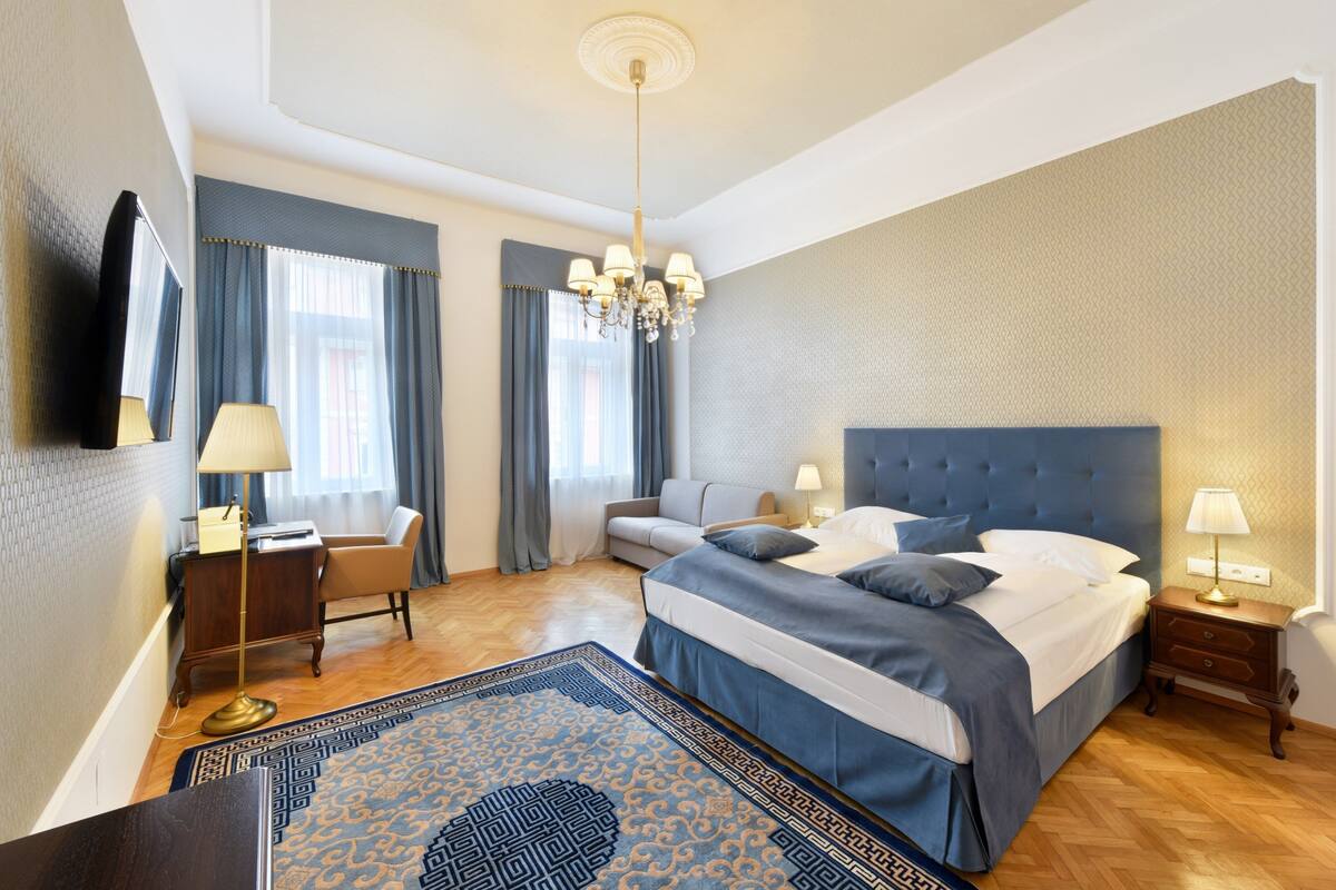 Une chambre d’hôtel avec un grand lit, un bureau, une chaise et un téléviseur fixé au mur.