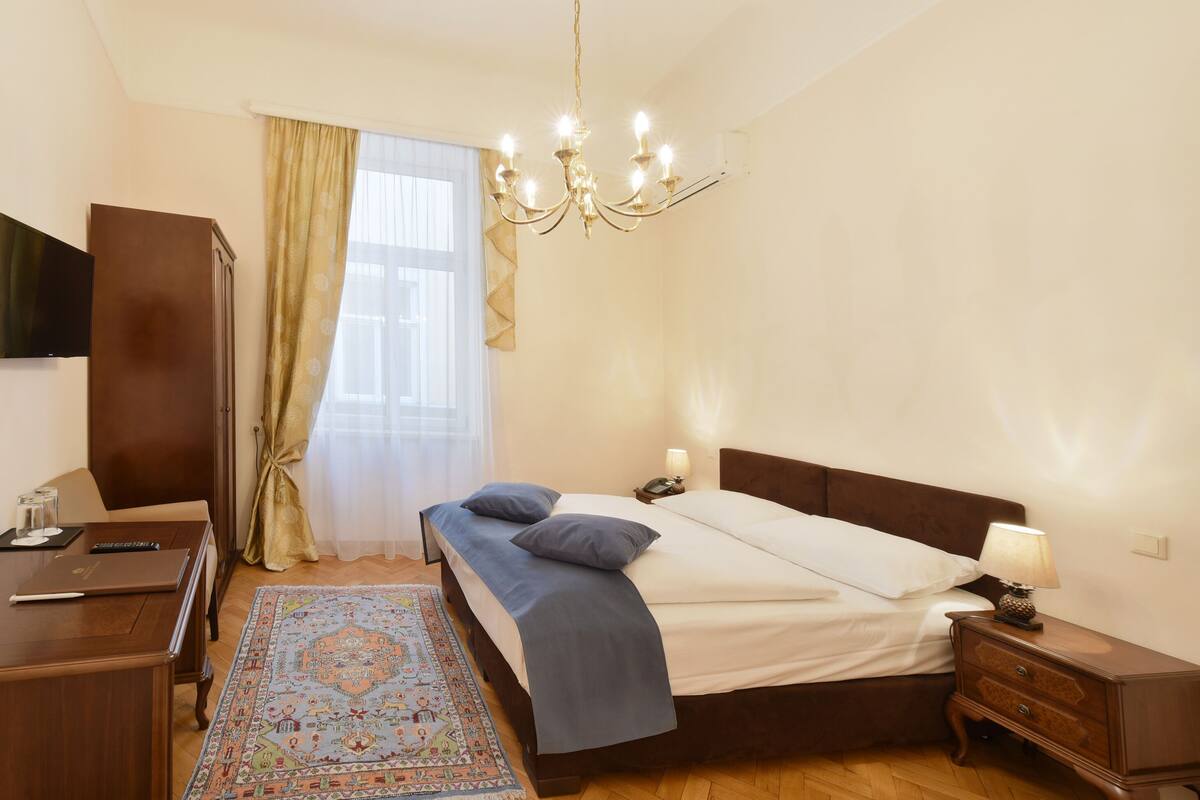 Une chambre à coucher comprenant un lit, une table de chevet, une lampe et un bureau avec une chaise.
