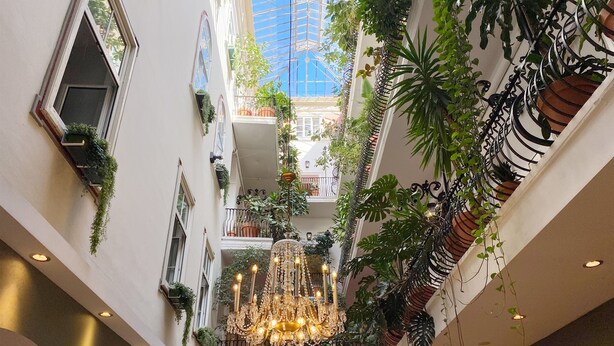 Een meerlaags atrium met een grote kroonluchter, potplanten en balkons.