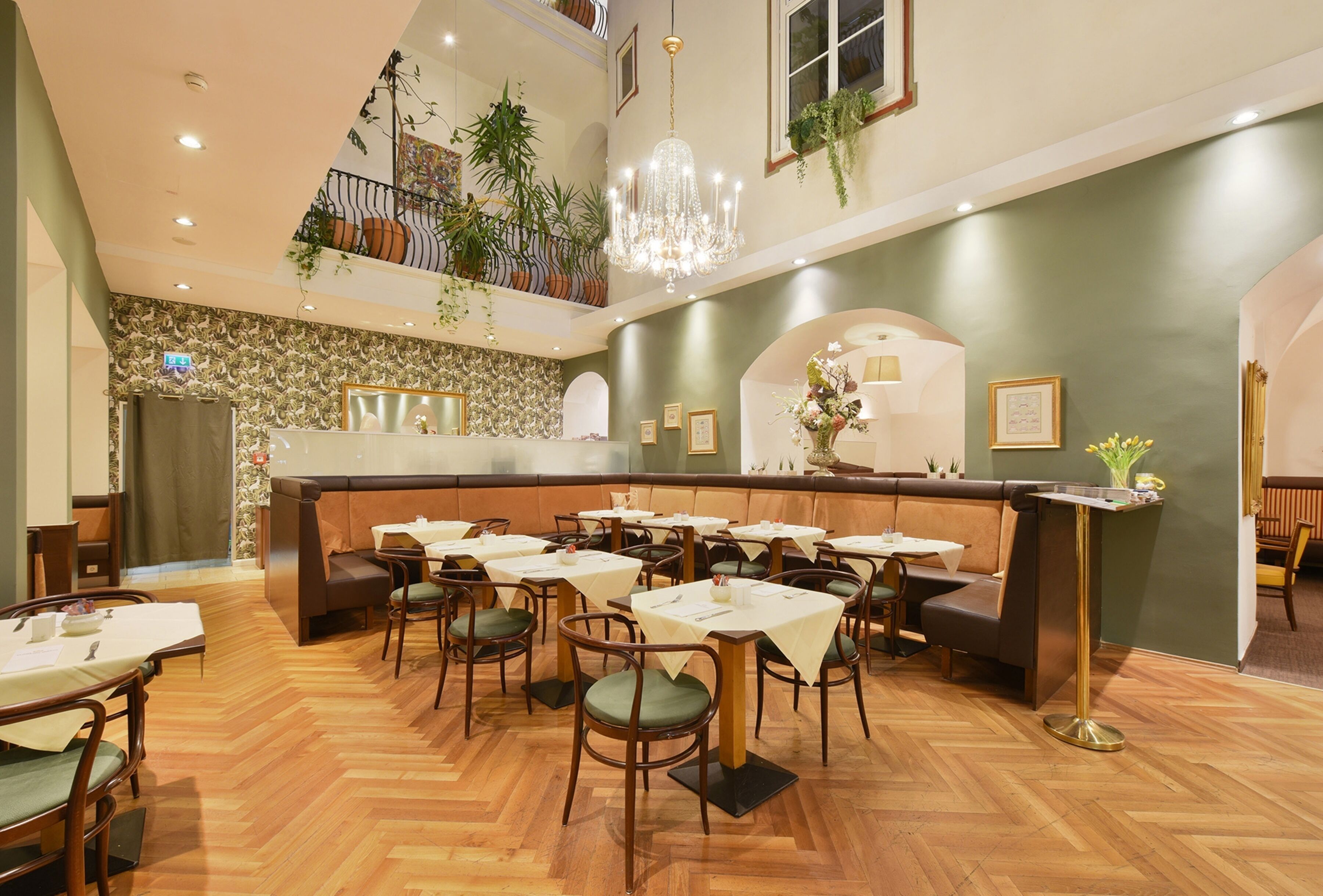 A restaurant with a high ceiling, wooden flooring, and a central seating area with tables and chairs.