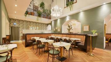 A restaurant with a high ceiling, wooden flooring, and a central seating area with tables and chairs.