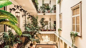 Een meerlaags atrium met verschillende potplanten, een kroonluchter en een zithoek.