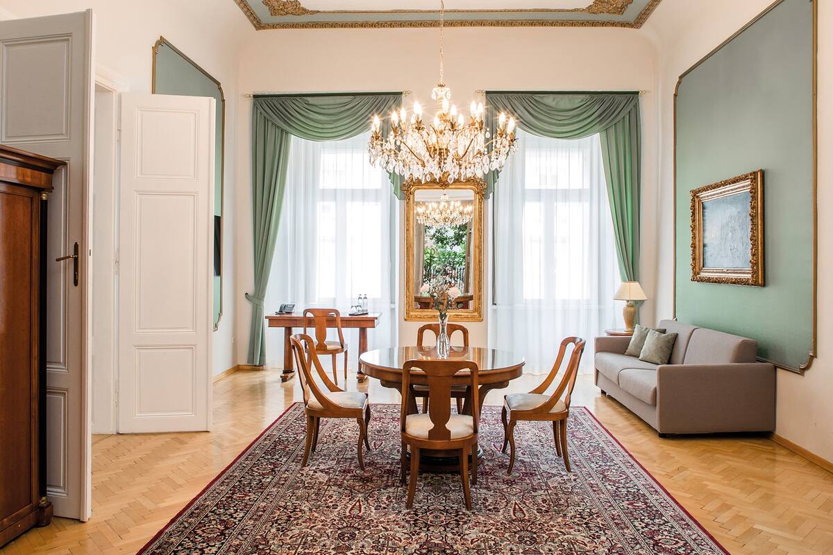 Un espace repas comprenant une table ronde, des chaises, un lustre et un grand miroir.
