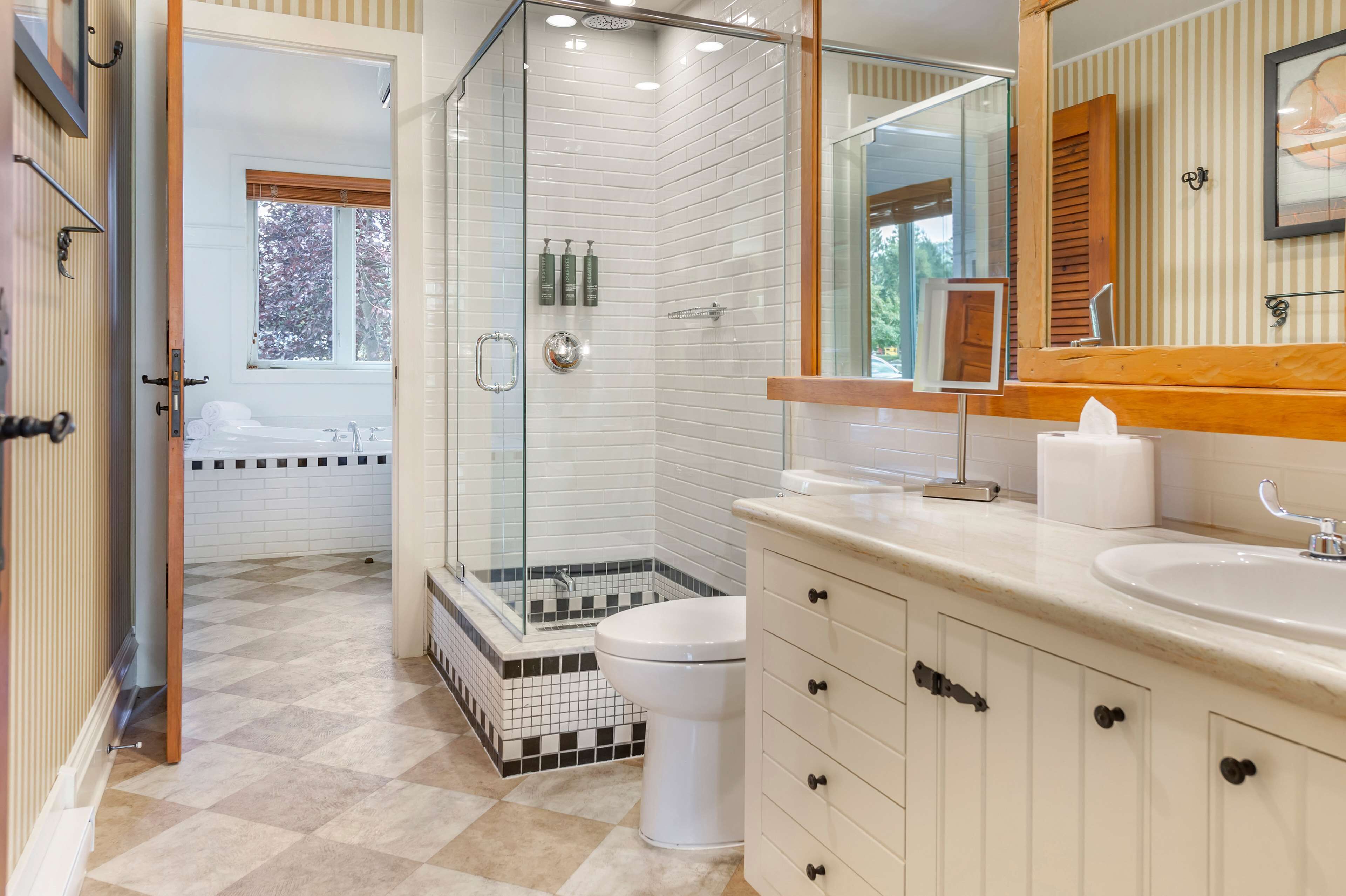 A modern bathroom with a glass-enclosed shower, a white toilet, and a vanity with a mirror.