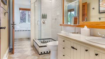 A modern bathroom with a glass-enclosed shower, a white toilet, and a vanity with a mirror.