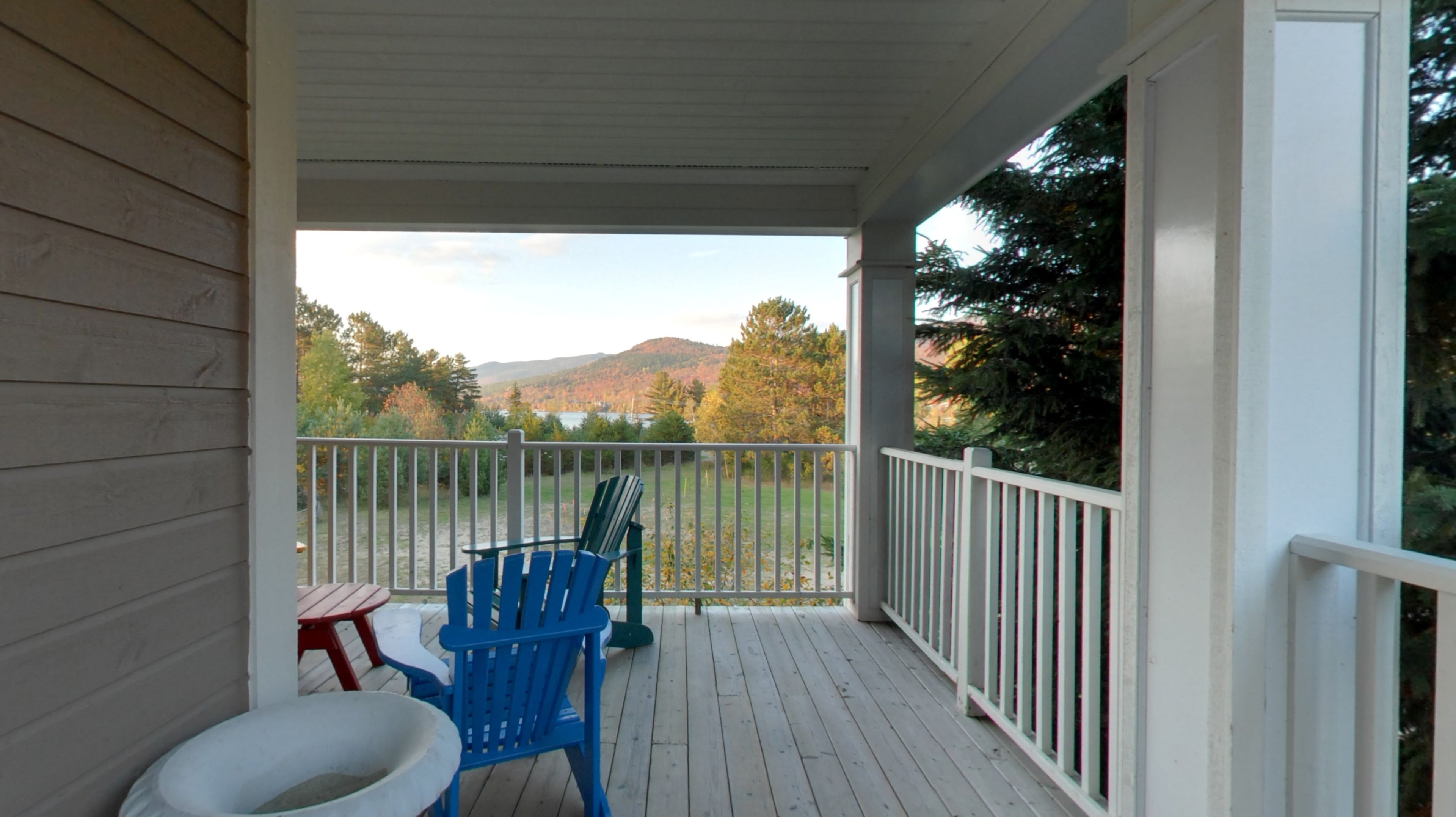 A covered porch with a view of a forest and mountains.