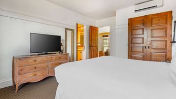 Une chambre d’hôtel avec un grand lit, une commode en bois, une télévision et un miroir.