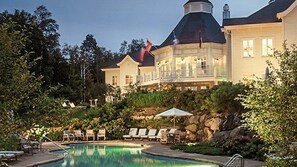 A resort with a swimming pool, lounge chairs, and a large building with a distinctive dome roof. - Hilton Grand Vacations Club Tremblant Canada (Mont-Tremblant)