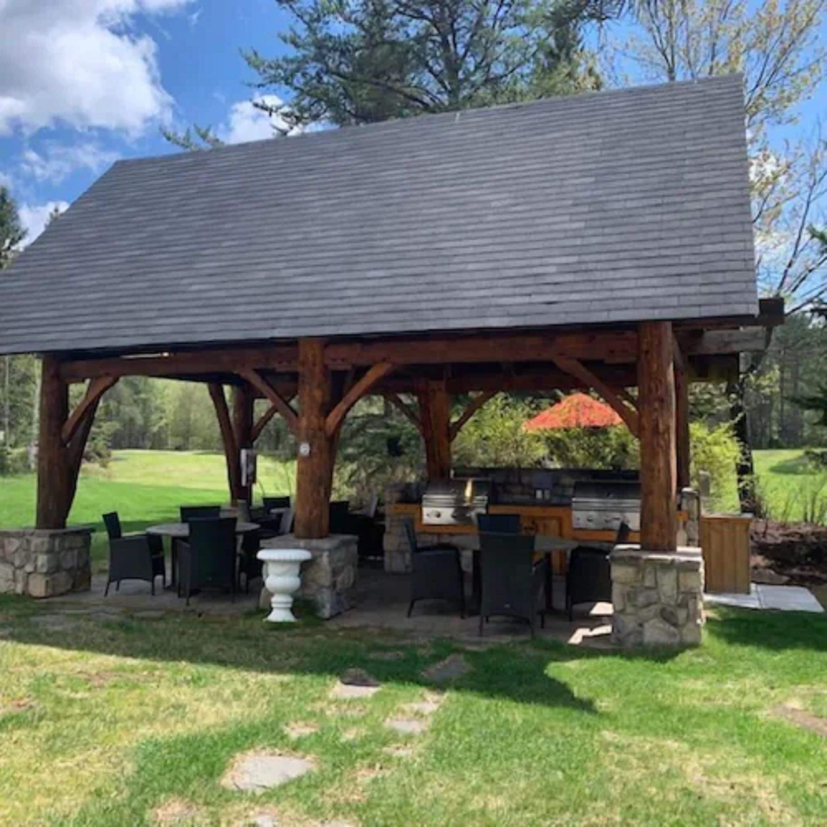 Un espace extérieur abrité, doté de piliers en pierre, d’un barbecue et de sièges pour se détendre en plein air.
