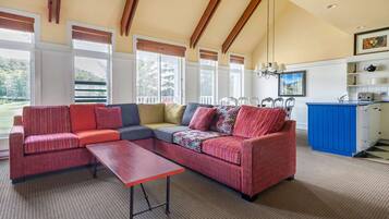 A spacious living area with a sectional sofa, a coffee table, and a kitchen area with blue cabinets and white appliances.