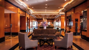 A lobby with a reception desk, a large floral arrangement, and seating area with sofas and armchairs.