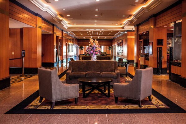 A lobby with a reception desk, a large floral arrangement, and seating area with sofas and armchairs.