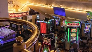 A casino floor with slot machines, a large chandelier, and a neon sign for Dragon's Lair.