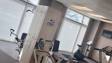 Ein Fitnessstudio mit verschiedenen Trainingsgeräten, darunter Laufband, Crosstrainer und Kraftgeräte.