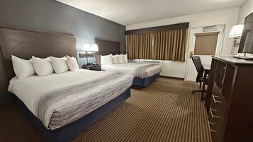 Una habitación de hotel con dos camas, un escritorio, una silla y un televisor.
