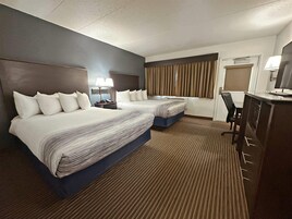 Una habitación de hotel con dos camas, un escritorio, una silla y un televisor.