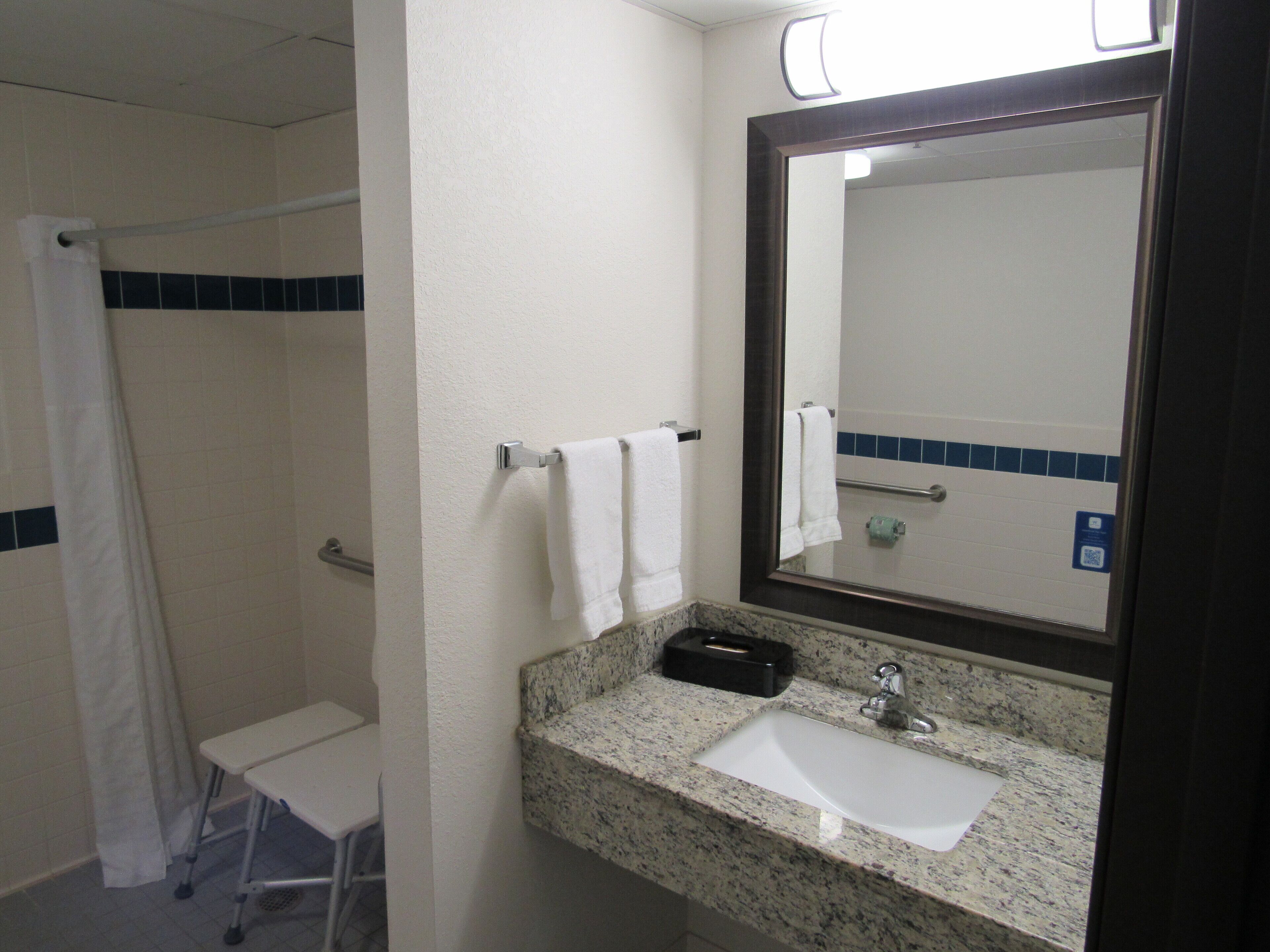 Une salle de bain équipée d’un lavabo, d’un miroir, d’un porte-serviettes et d’un espace douche.