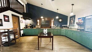 Une cuisine moderne avec des meubles de couleur verte, une table en bois et un tableau noir sur lequel est écrit le mot « Bienvenue ».