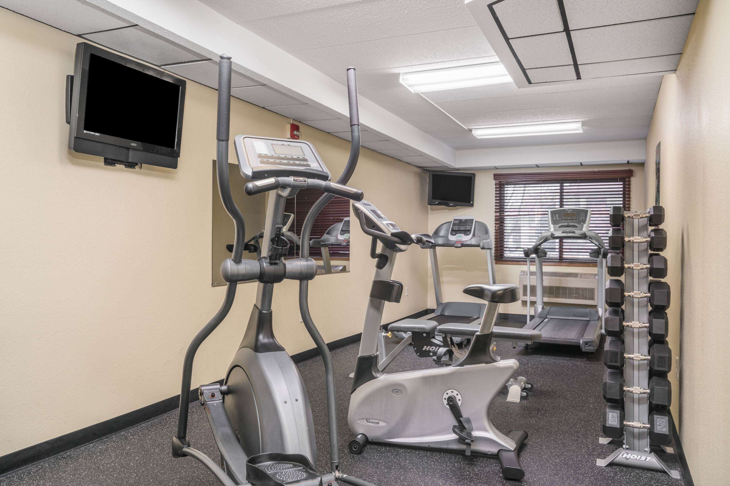 Une salle de sport équipée de vélos d’appartement, de tapis de course et d’un banc de musculation.