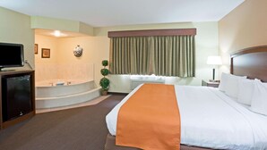 A hotel room with a large bed, a TV, a bathtub, and a window with curtains. - AmericInn by Wyndham Fargo West Acres (Fargo)