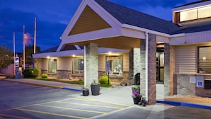 A hotel entrance with a covered patio, brick facade, and a parking area with marked spaces. - AmericInn by Wyndham Fargo West Acres (Fargo)