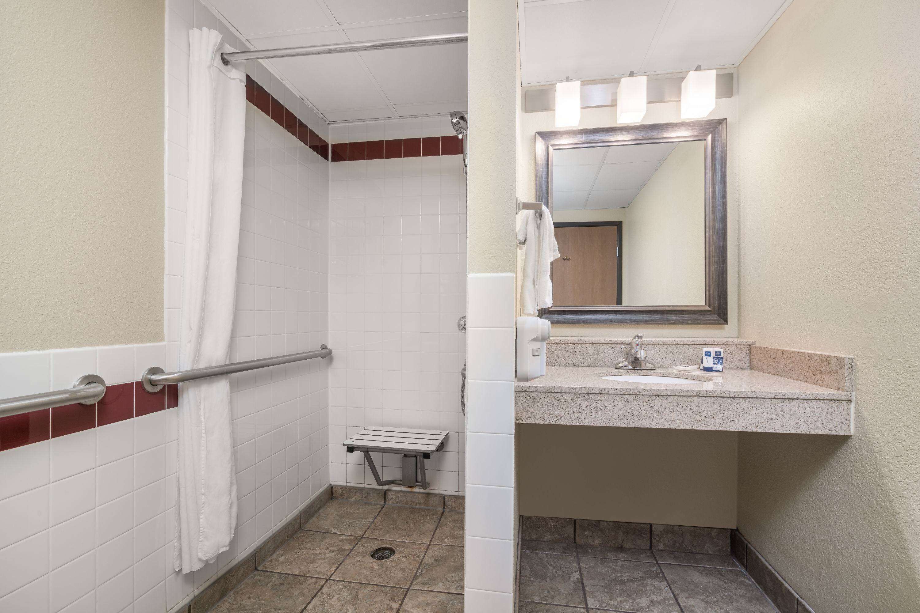 Un baño con ducha, un banco, un lavabo y un espejo.