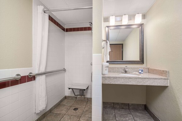 Un baño con ducha, un banco, un lavabo y un espejo.