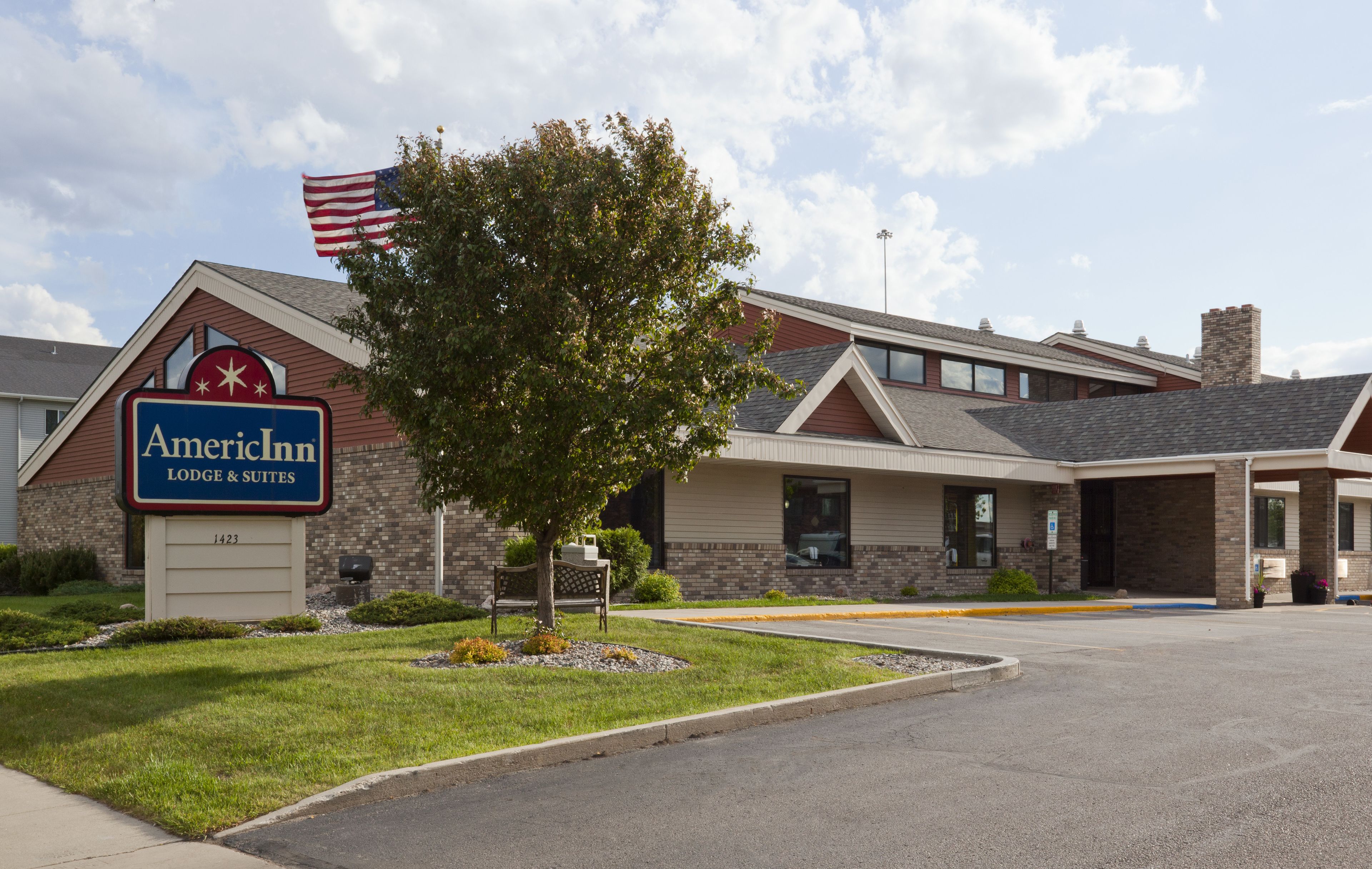 An American Inn with a sign, a flag, and a well-maintained lawn.