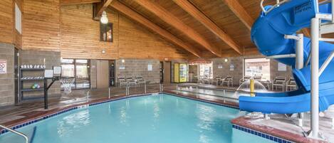 An indoor swimming pool with a blue water slide and a diving platform.