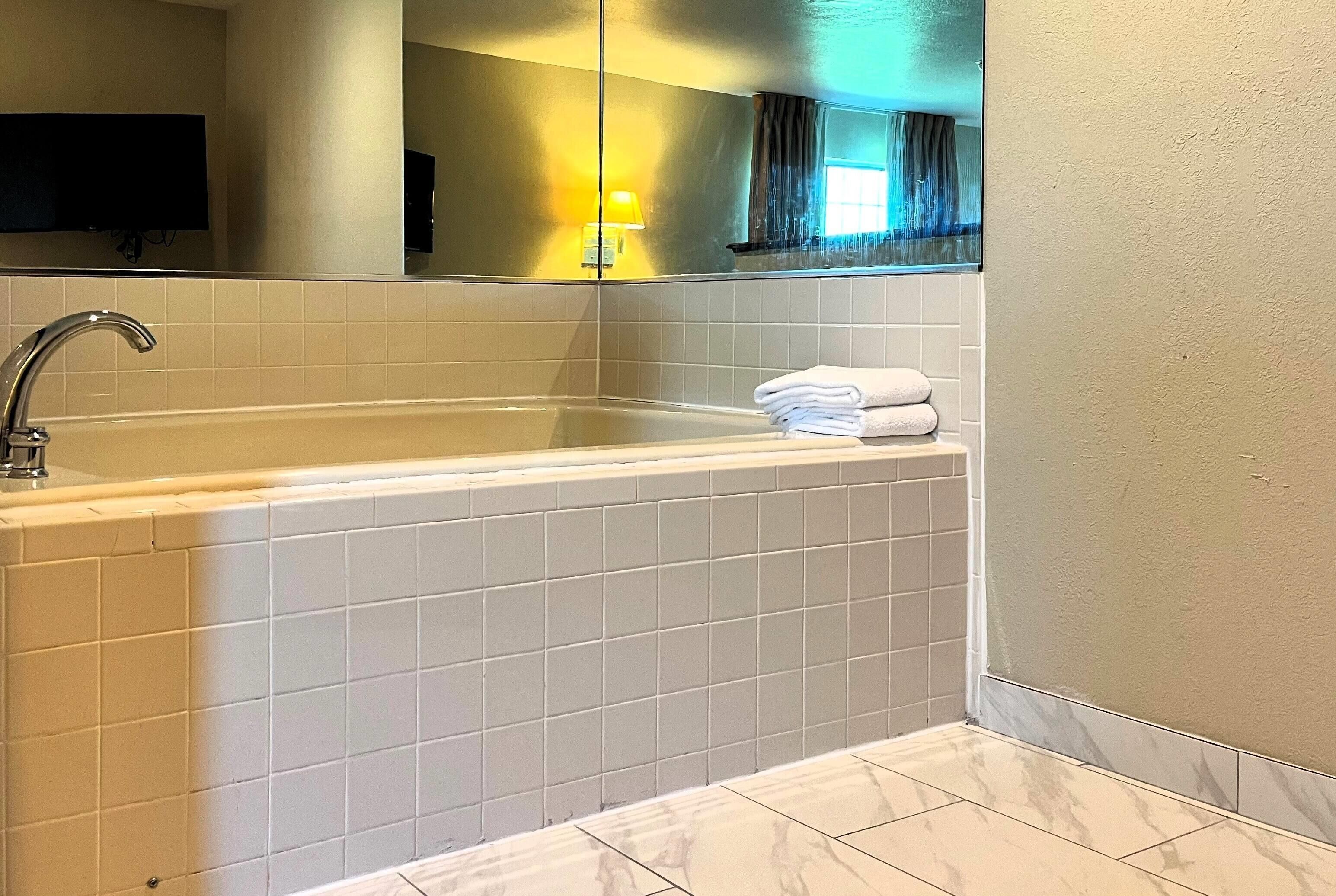 A bathroom with a bathtub, a sink, and a mirror.