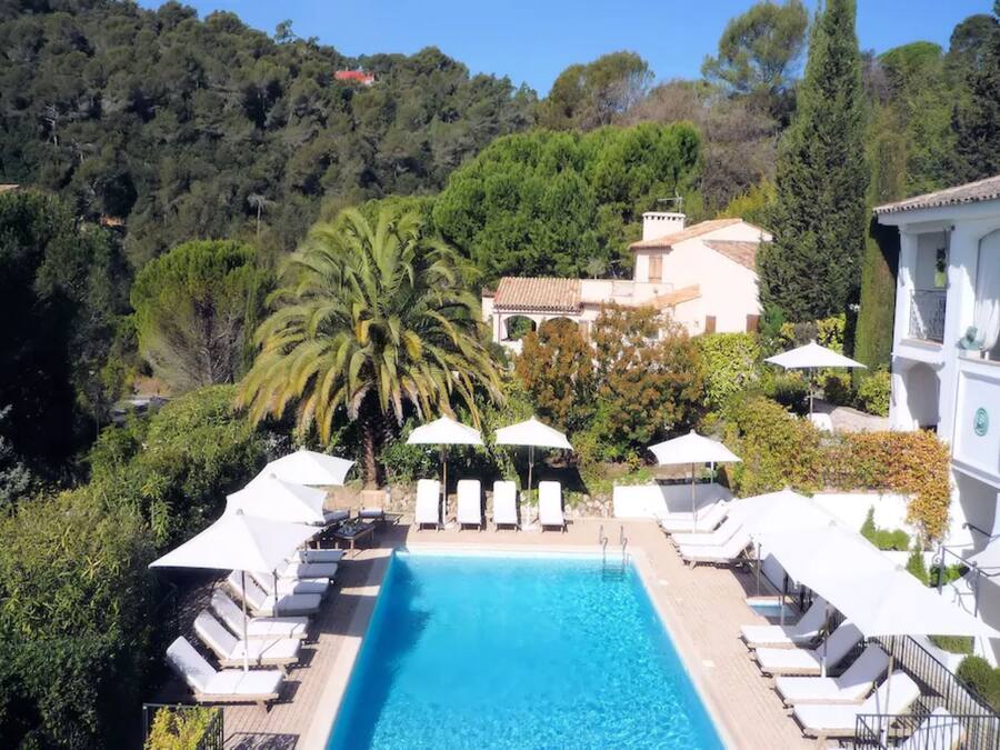Una piscina al aire libre, sombrillas, sillones reclinables de piscina