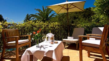 Enjoy a serene outdoor dining experience surrounded by lush greenery and palm trees.