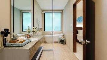 A modern bathroom with a large mirror, a bathtub, and a vanity with a sink and countertop.